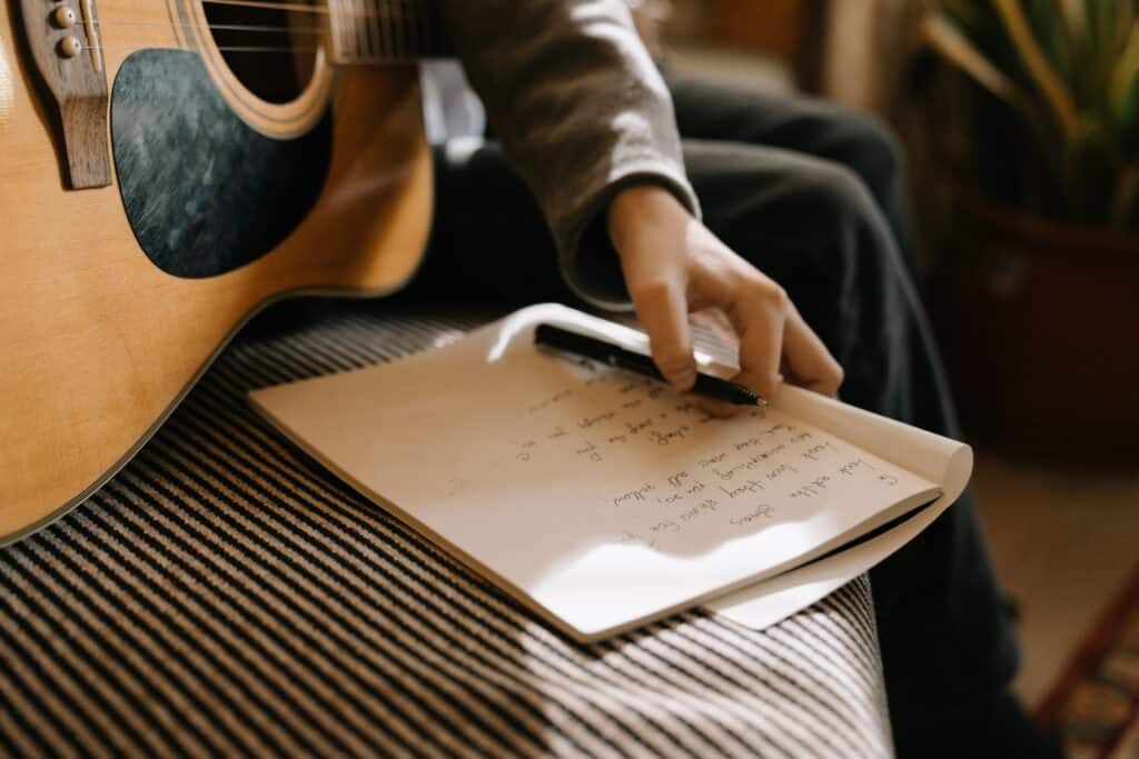 guitar player holding pen and notebook with song lyrics