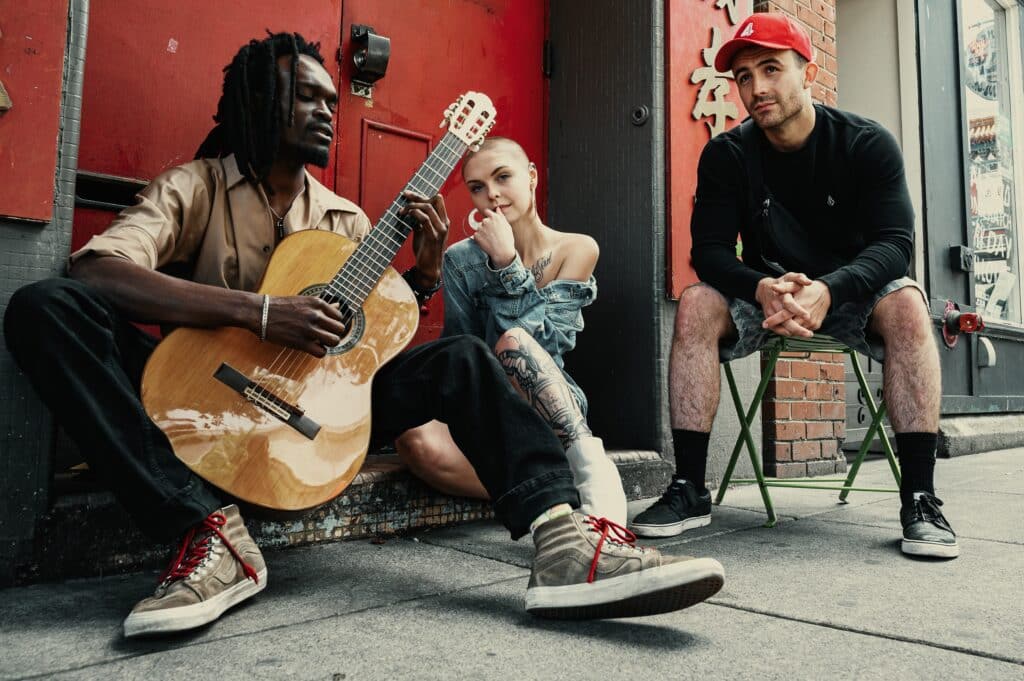 musicians sitting next to each other on the sidewalk