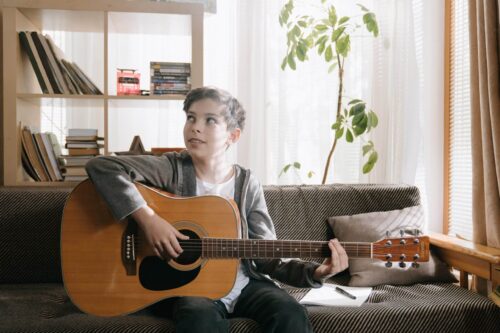 boy practicing the guitar in living room