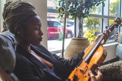 woman holding a violin next to a window